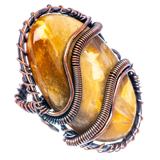 Wire wrap ring with amber petrified palm root slabs and oxidized copper coils, angled view