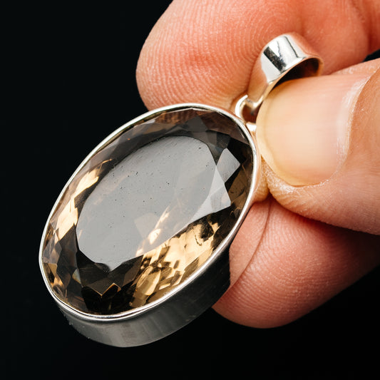 Side view of oval faceted smoky quartz pendant in sterling silver setting, loop bail