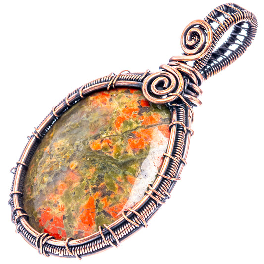 Unakite wire-wrap pendant angled view, green-and-red stone in oxidized copper spiral frame