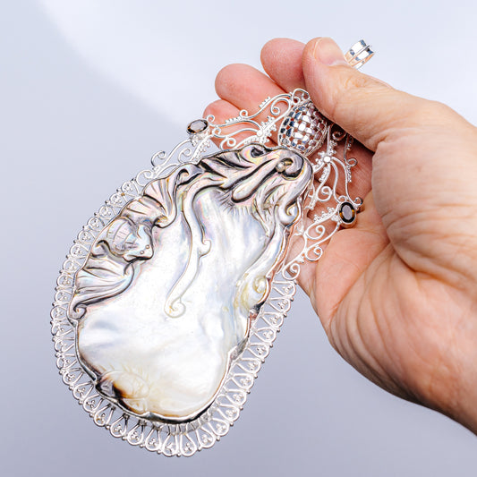 Mother-of-pearl teardrop pendant with .925 sterling silver filigree and dark gemstone accents