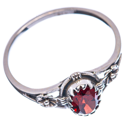 Sterling silver ring showing round garnet red center stone with ornate side details