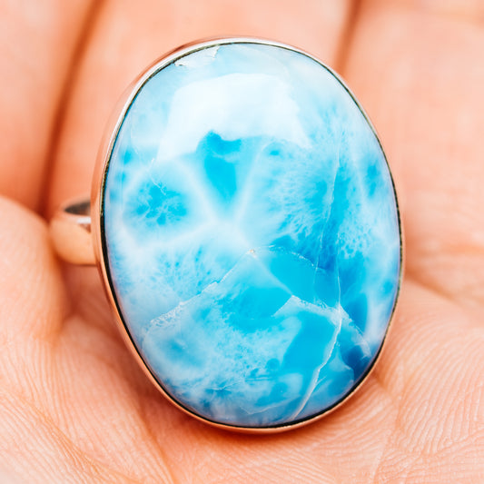 Blue larimar oval cabochon ring with silver bezel, shown face-on on fingertip