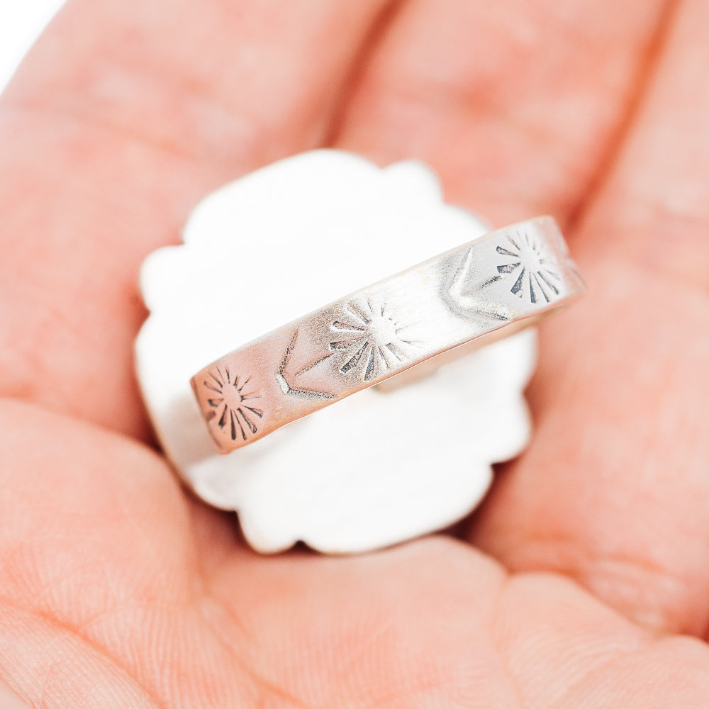 Adjustable sterling silver band ring with engraved sunburst pattern across the top