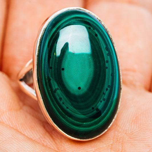 Oval malachite gemstone sterling silver ring on finger, dark green swirls with dot inlays.