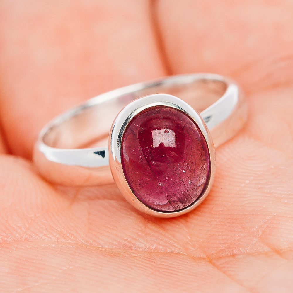 Oval pink tourmaline sterling silver ring with bezel, worn on finger, size 7