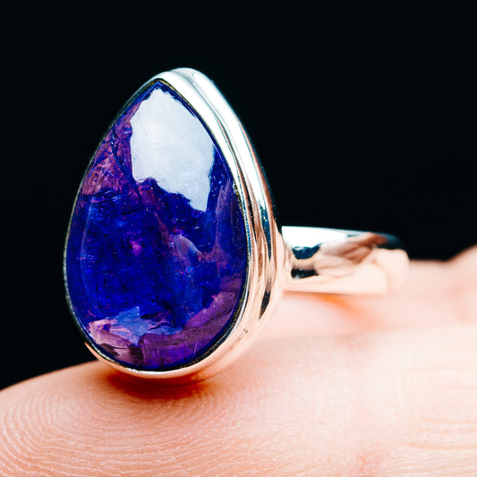 Oval blue gemstone ring with silver bezel setting, side view on finger