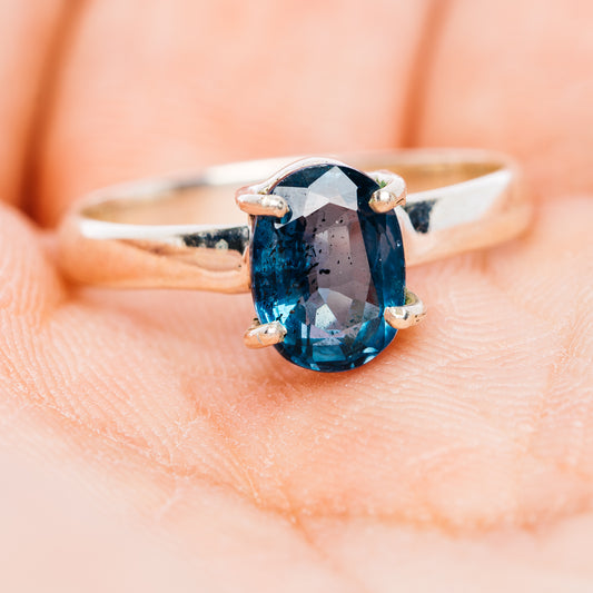 Oval faceted deep teal kyanite ring, sterling silver band with four prongs