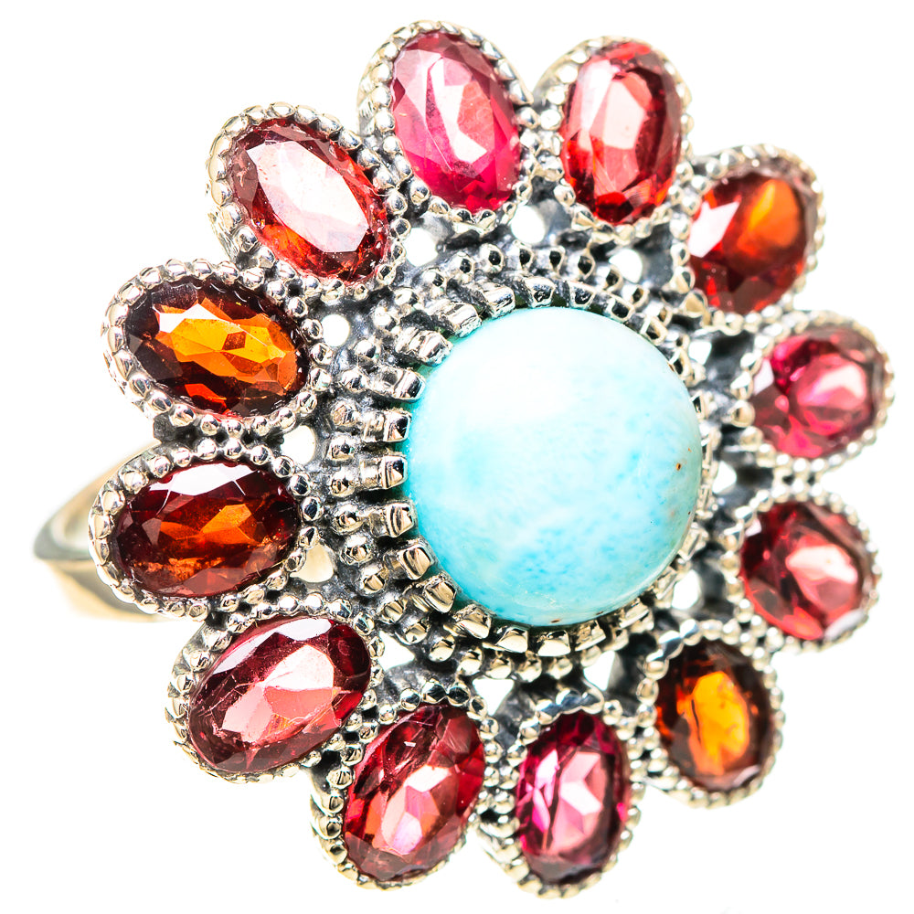 Oval light-blue cabochon ring with surrounding red faceted stones in silver setting