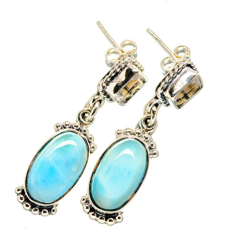 Sterling silver drop earrings with blue oval gemstones in ornate bezels and chain dangles