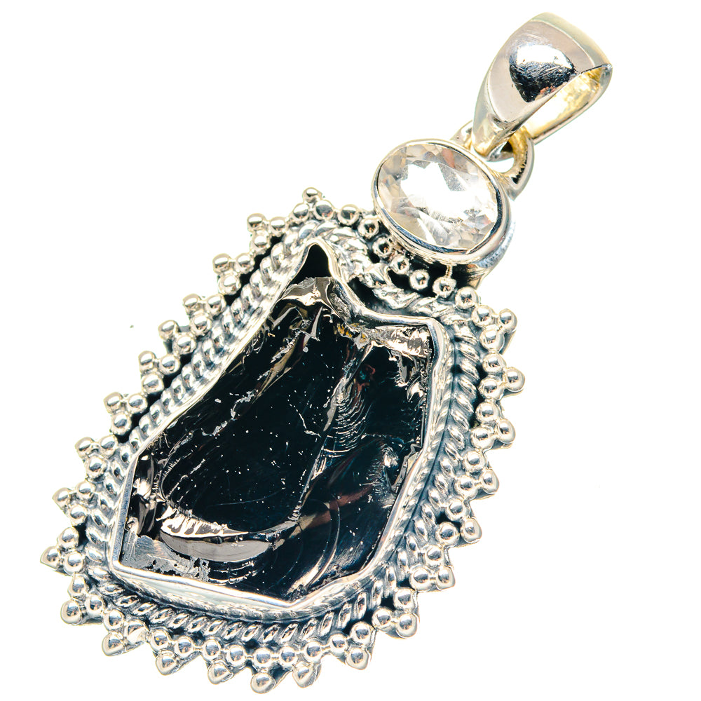 Ornate silver teardrop pendant featuring rough dark stone and clear round gemstone