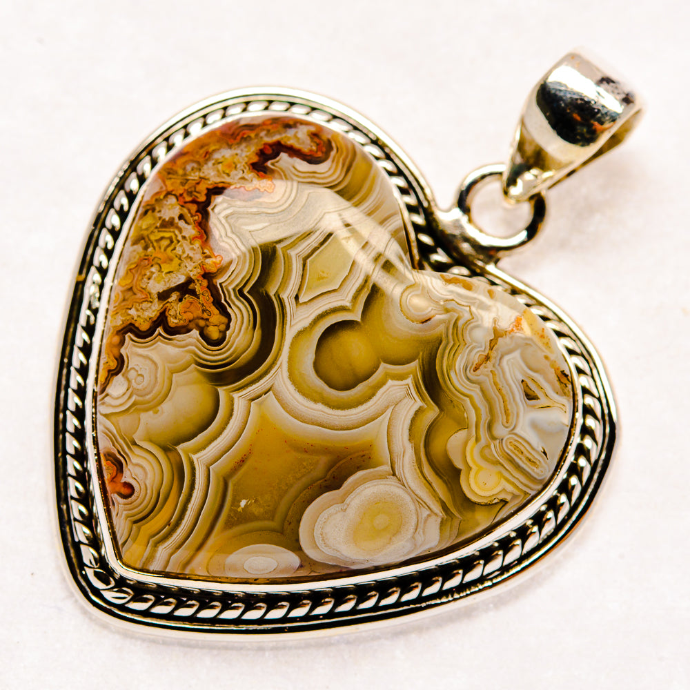 Heart-shaped agate pendant featuring layered brown and cream patterns in sterling silver
