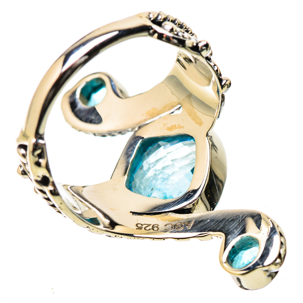 Polished metal ring with blue oval center stone and matching blue accents, openwork band