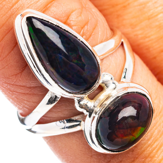 Sterling silver opal ring on hand with large oval dark blue center and red-black stone