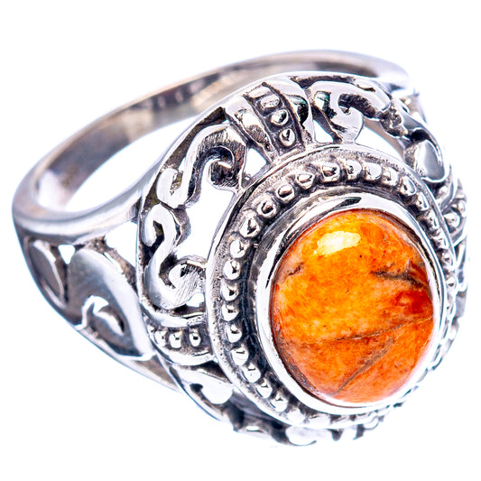 Sterling silver filigree ring featuring an orange oval cabochon coral with scroll details.