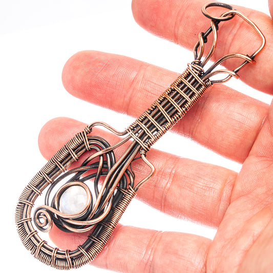 Oxidized copper wire-wrapped pendant with oval iridescent moonstone cabochon.