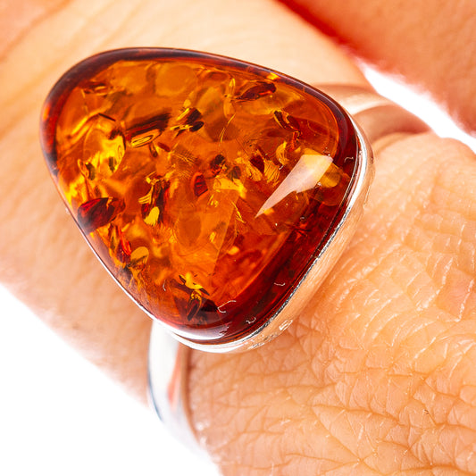 Amber teardrop ring with silver bezel and glossy golden amber cabochon.
