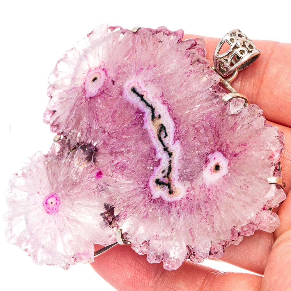 Pink solar quartz pendant slice with silver bail, close-up on hand