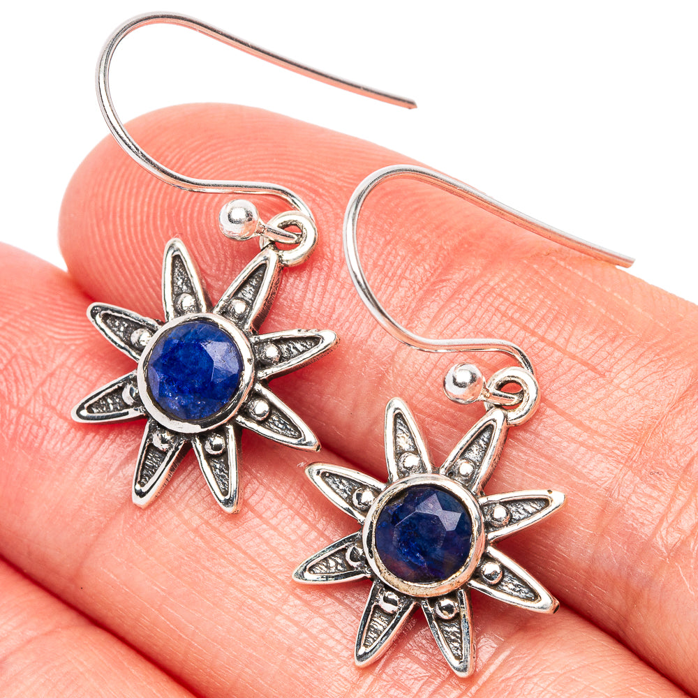 Sterling silver flower drop earrings with round blue gemstone centers, close-up detail