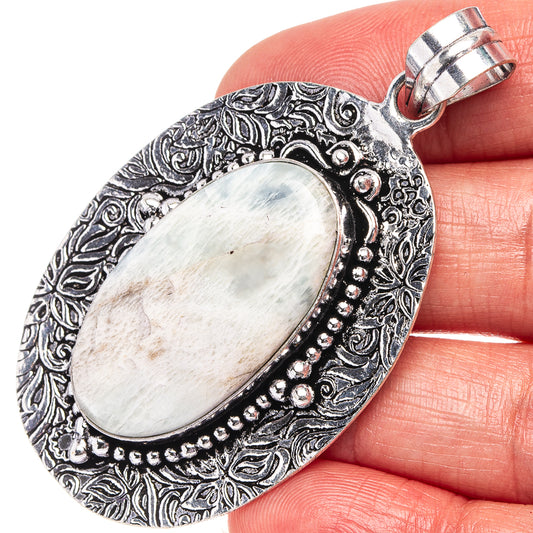German silver oval scolescite pendant with ornate border and pale white stone, top bail