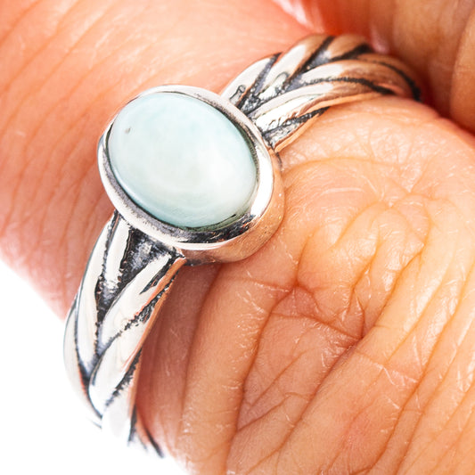 Sterling silver dainty ring on finger, oval light-blue larimar cabochon bezel detail