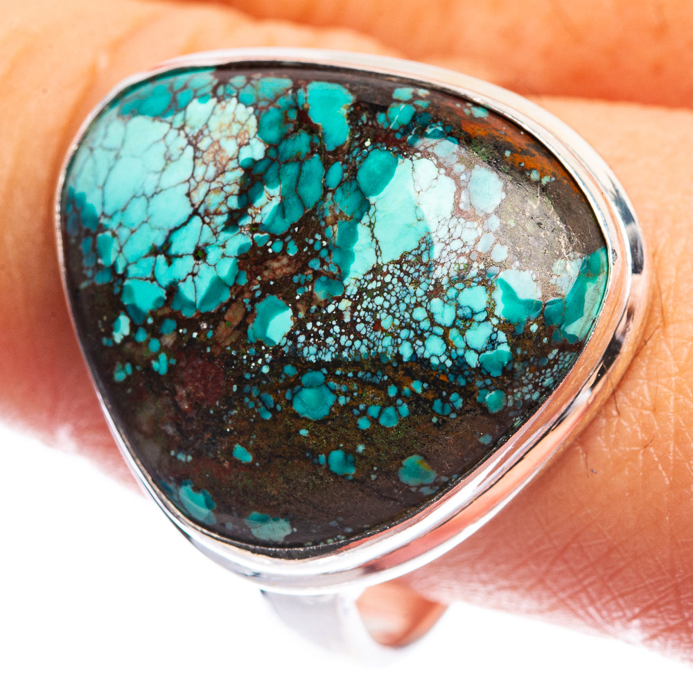 Sterling silver ring with oval turquoise cabochon, worn on finger, dark speckled matrix