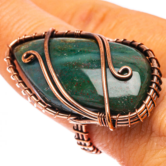 Oxidized copper wire ring on wrist with dark green teardrop stone and spiral details