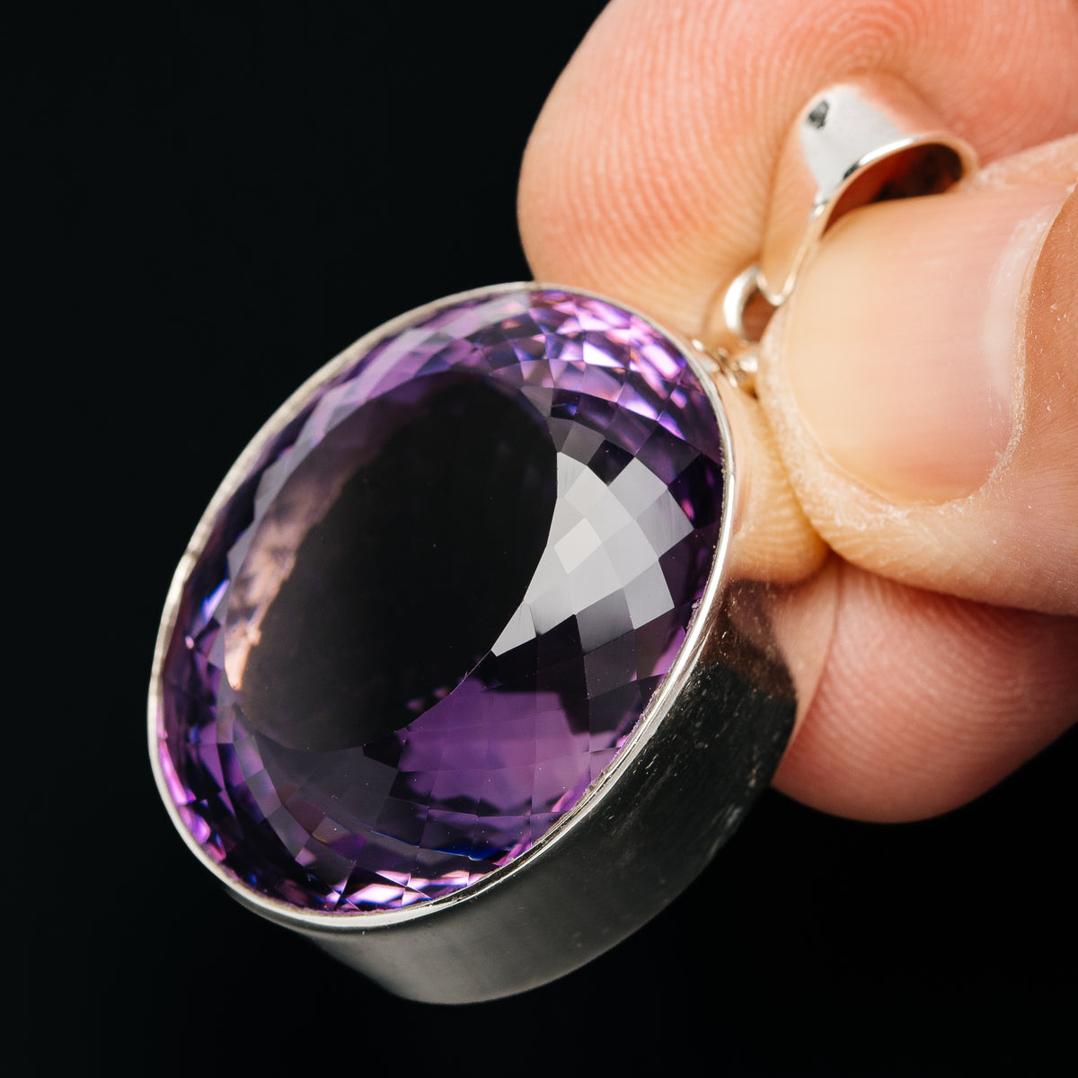 Sterling silver oval amethyst pendant, faceted purple stone in side bezel view
