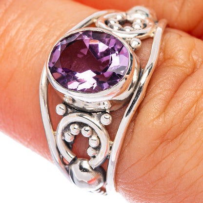 Sterling silver amethyst ring close-up with faceted round-oval gem and side scrollwork
