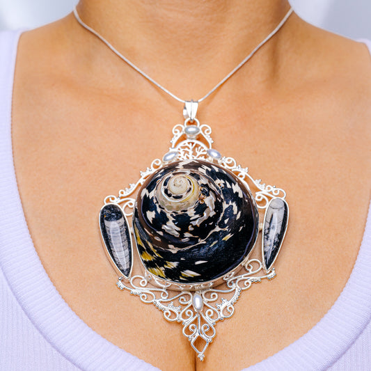 Sterling silver pendant with dark fossil-shell center and ornate filigree setting