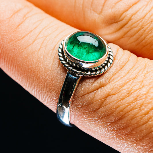 Zambian emerald ring with oval green gemstone and braided silver bezel on finger
