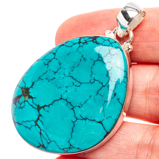 Turquoise oval pendant in silver bezel with dark vein marbling, attached bail