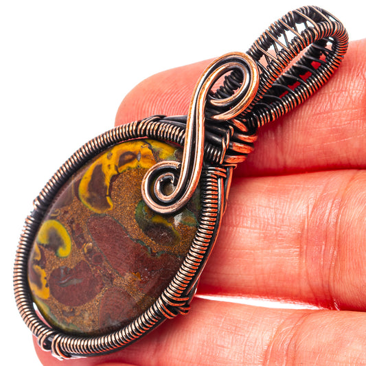 Oval jasper stone wire-wrapped in oxidized copper, close-up on top bail