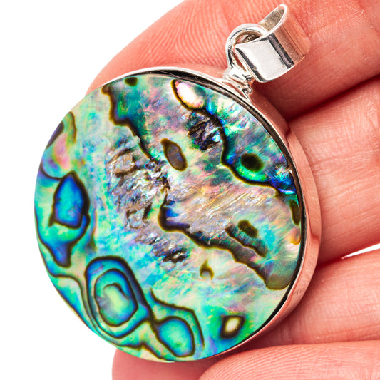 Round abalone shell pendant in iridescent blue-green with sterling silver bail.