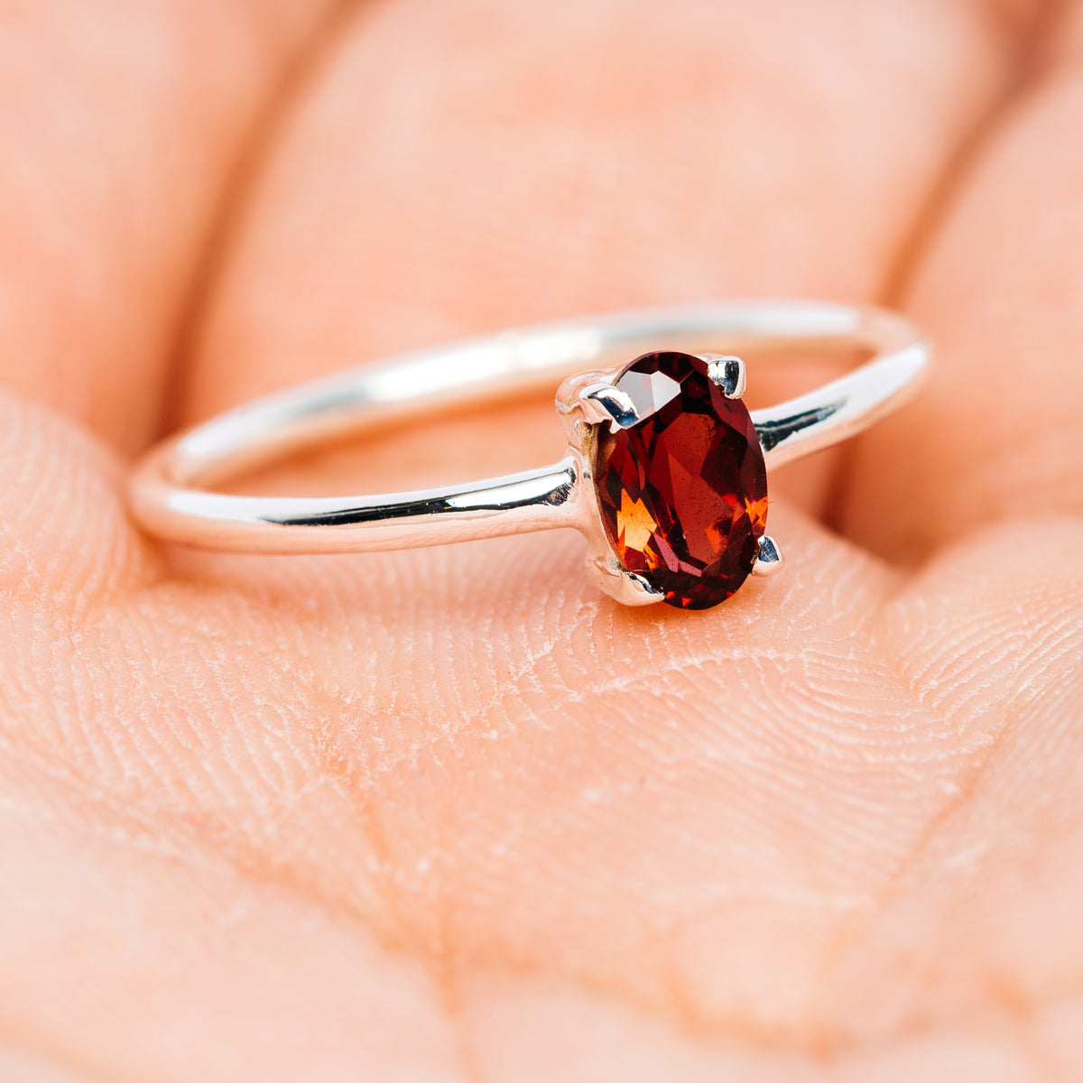 Garnet stackable sterling silver ring with oval dark red gemstone on slim polished band