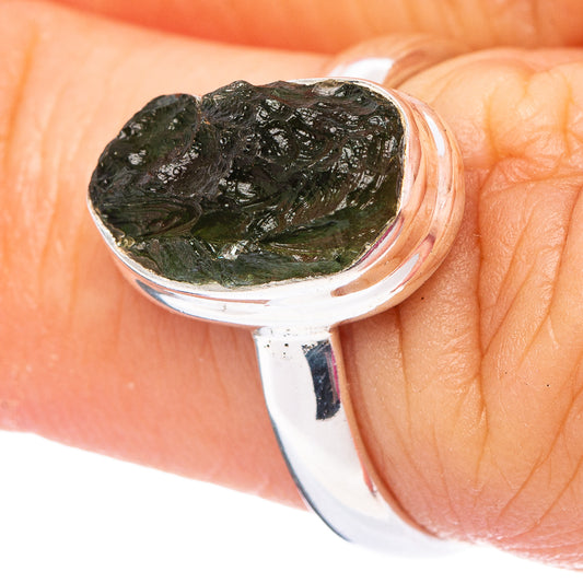 Sterling silver moldavite ring on finger, oval dark green stone with texture
