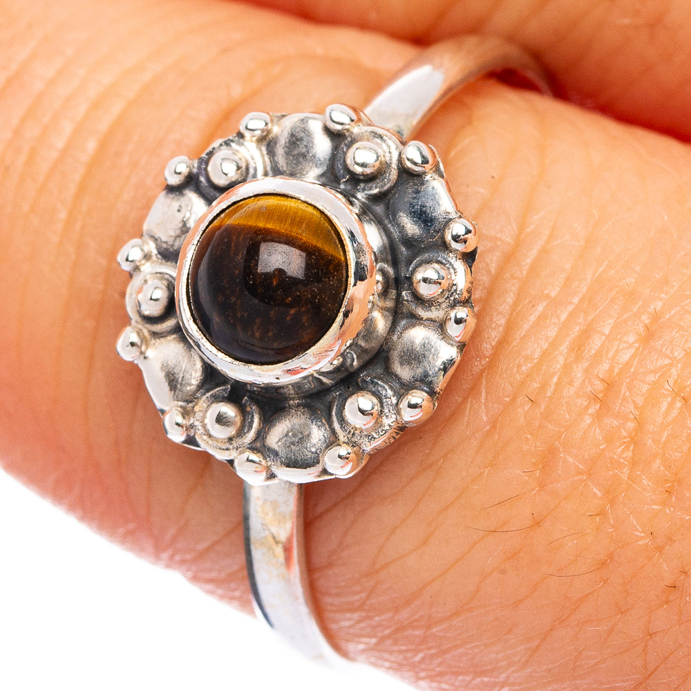 Sterling silver ring on finger with round tiger eye cabochon and beaded outer edge