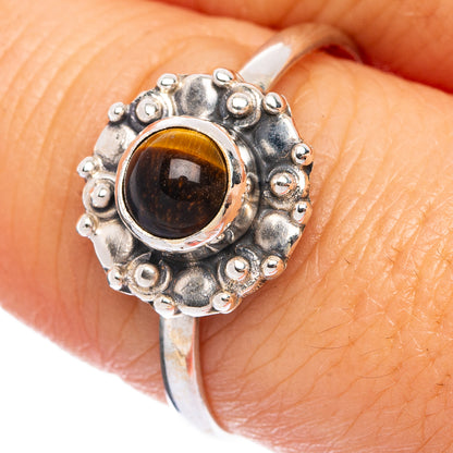 Sterling silver ring on finger with round tiger eye cabochon and beaded outer edge