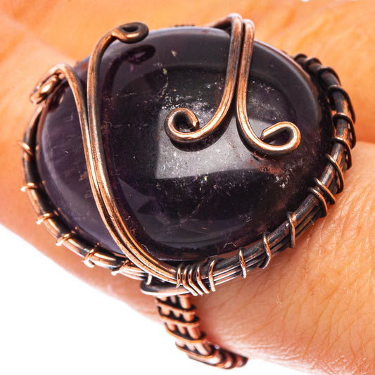 Amethyst cabochon ring with oxidized copper wire wrap, dark purple stone, raised scrolls