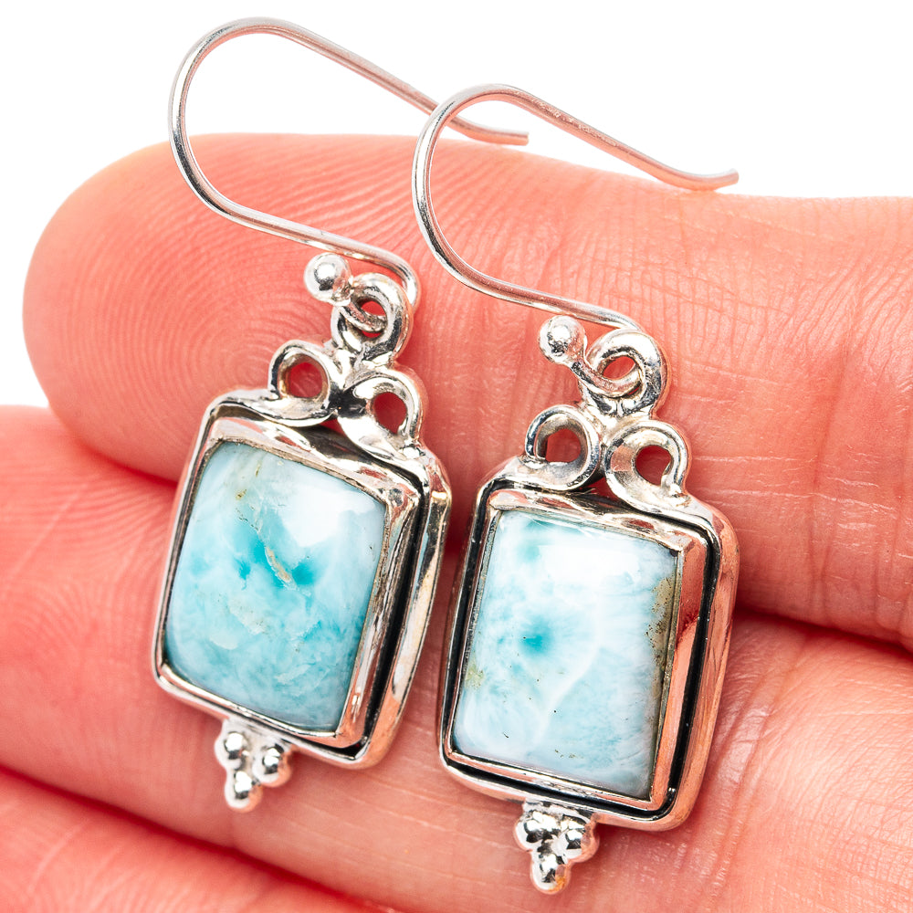 Sterling silver earrings with square blue larimar cabochons, dangling hooks, and scroll details