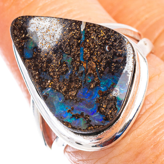 Sterling silver opal ring on finger, dark boulder opal with vivid blue patches