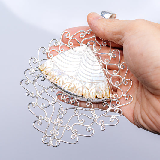Iridescent mother-of-pearl pendant in openwork sterling silver filigree, teardrop shape.
