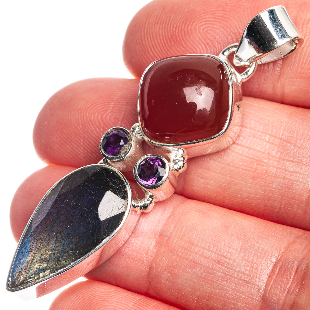 Sterling silver gemstone pendant close-up with red cabochon, purple stones, labradorite sheen