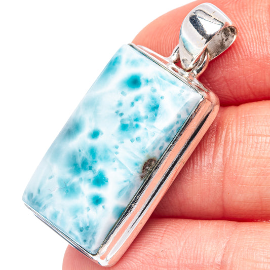 Rectangular larimar pendant with .925 sterling silver bezel, held in finger close-up