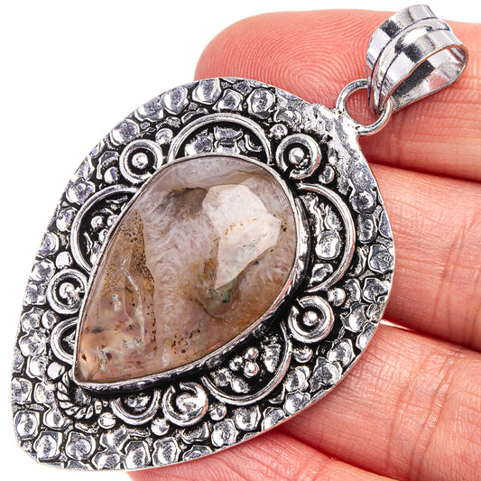 Close-up teardrop Montana agate pendant with silver-tone filigree bezel and hanging bail