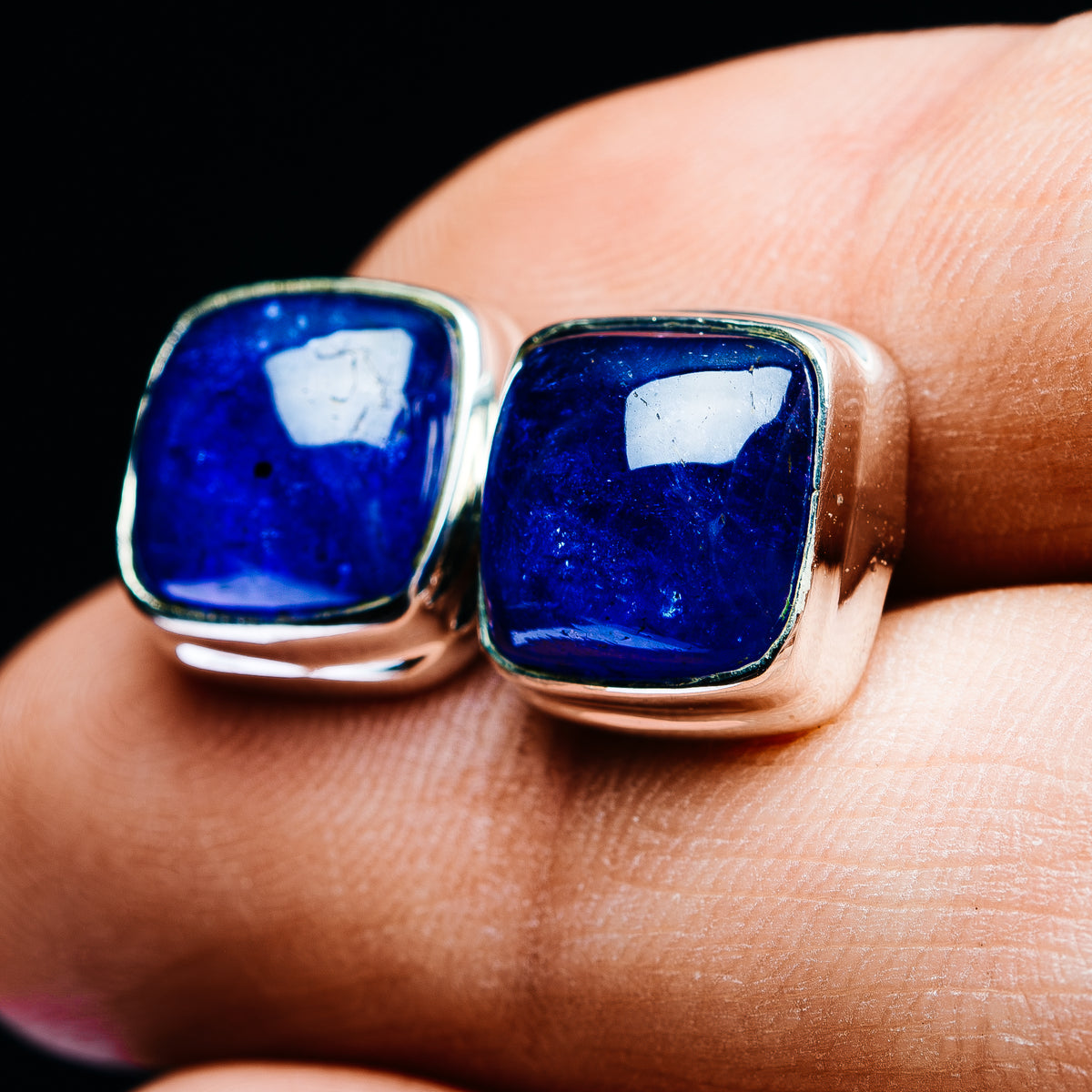 Close-up of square blue tanzanite studs with silver bezel frames