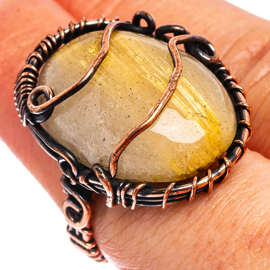 Oxidized copper wire wrap ring on finger, oval rutilated quartz stone with copper rim