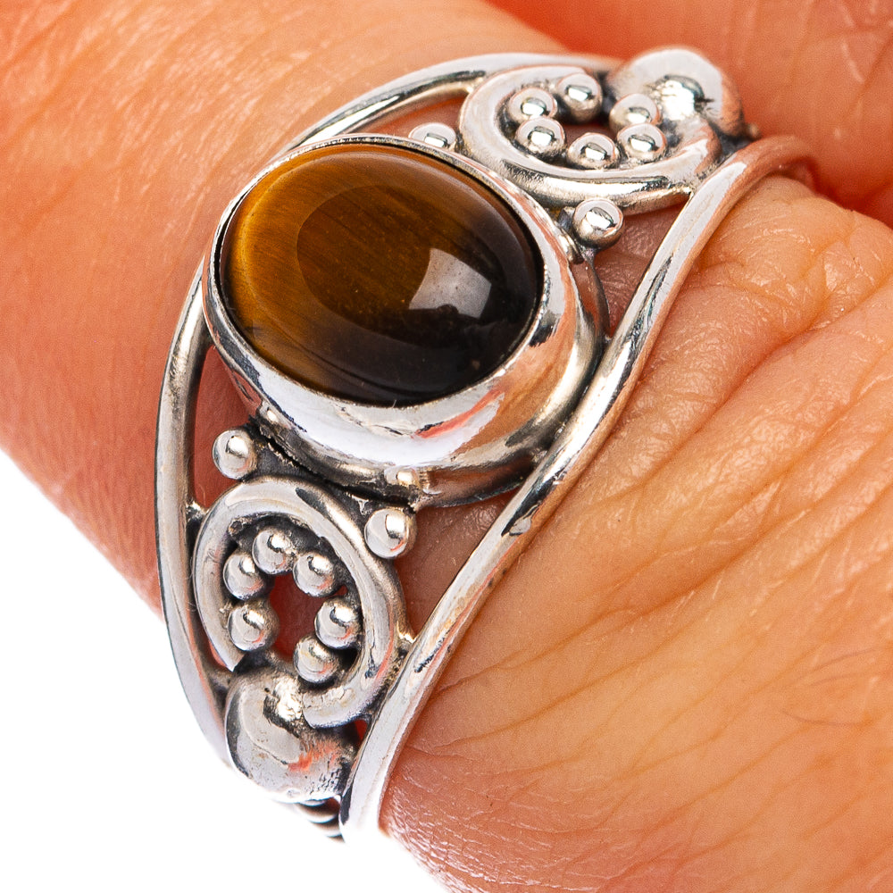 Sterling silver ring close-up: oval tiger eye cabochon with ornate bezel and scrollwork