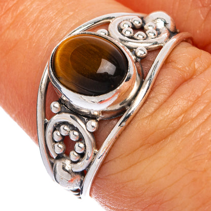 Sterling silver ring close-up: oval tiger eye cabochon with ornate bezel and scrollwork