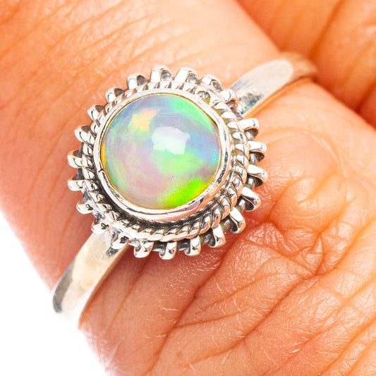 Round opal cabochon ring in sterling silver with spiked halo on finger.