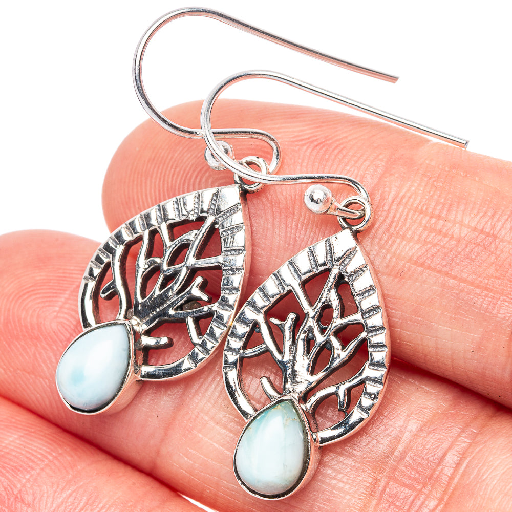Sterling silver tree earrings with larimar teardrop stones, close-up.